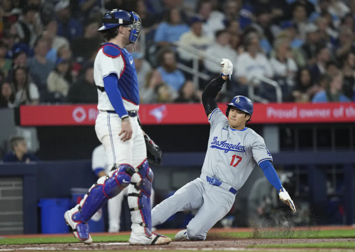 Los Angeles Dodgers' Shohei Ohtani (17) scores past Toronto Blue Jays catcher Danny Jansen (9) during the third inning of a baseball game in Toronto on April 26, 2024. (Nathan Denette/The Canadian Press via AP)