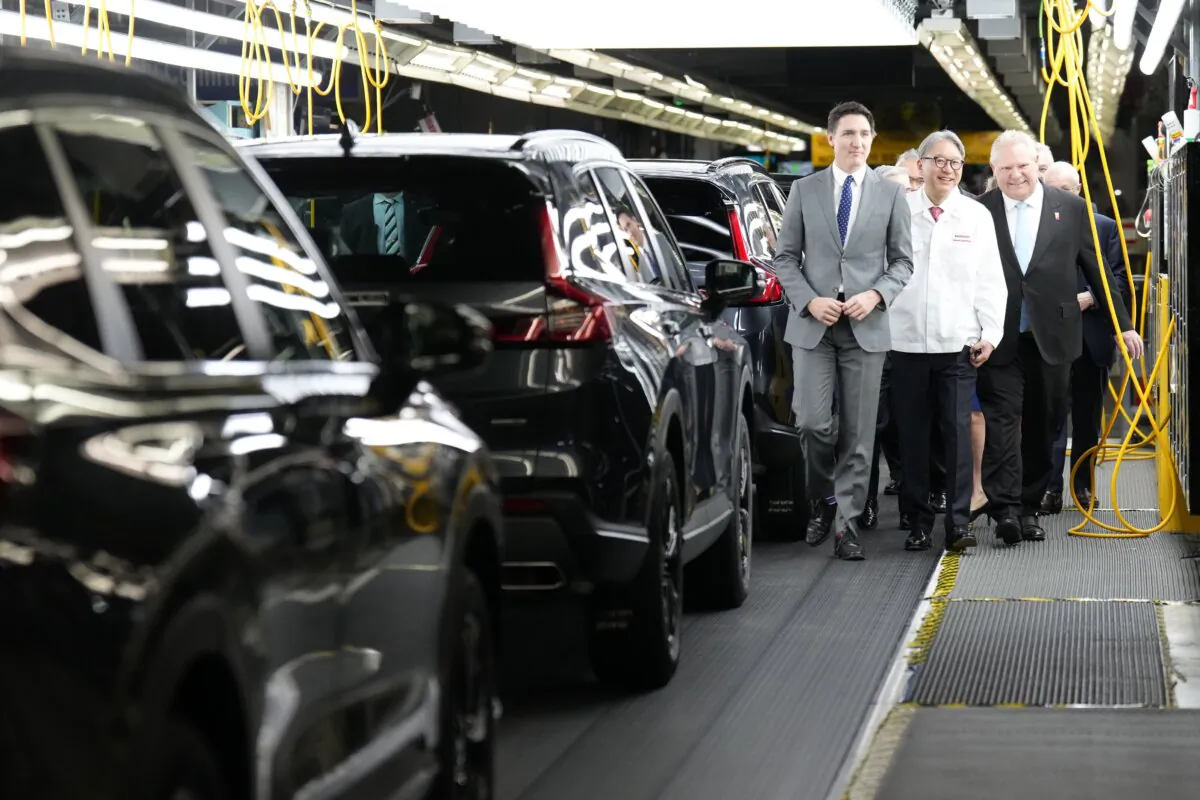 (L-R) Prime Minister Justin Trudeau, Honda executive Toshihiro Mibe, and Ontario Premier Doug Ford walk along an assembly line at an event announcing plans for a Honda electric vehicle battery plant in Alliston, Ont., on April 25, 2024. (The Canadian Press/Nathan Denette)