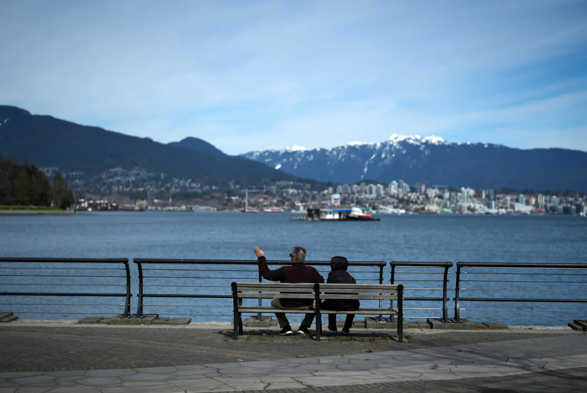A couple takes in the view from the seawall in Vancouver on March 29, 2023. (The Canadian Press/Darryl Dyck)