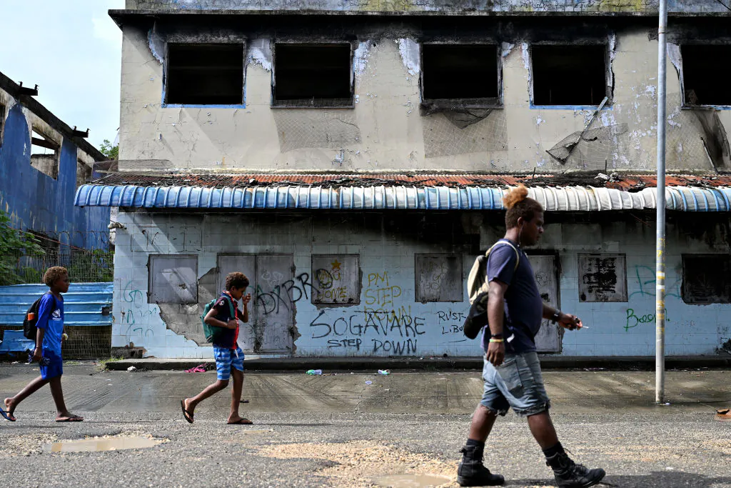 People walk past a derelict building in the Chinatown district of Honiara, the Solomon Islands capital, on April 16, 2024. (Saeed Khan/AFP via Getty Images)