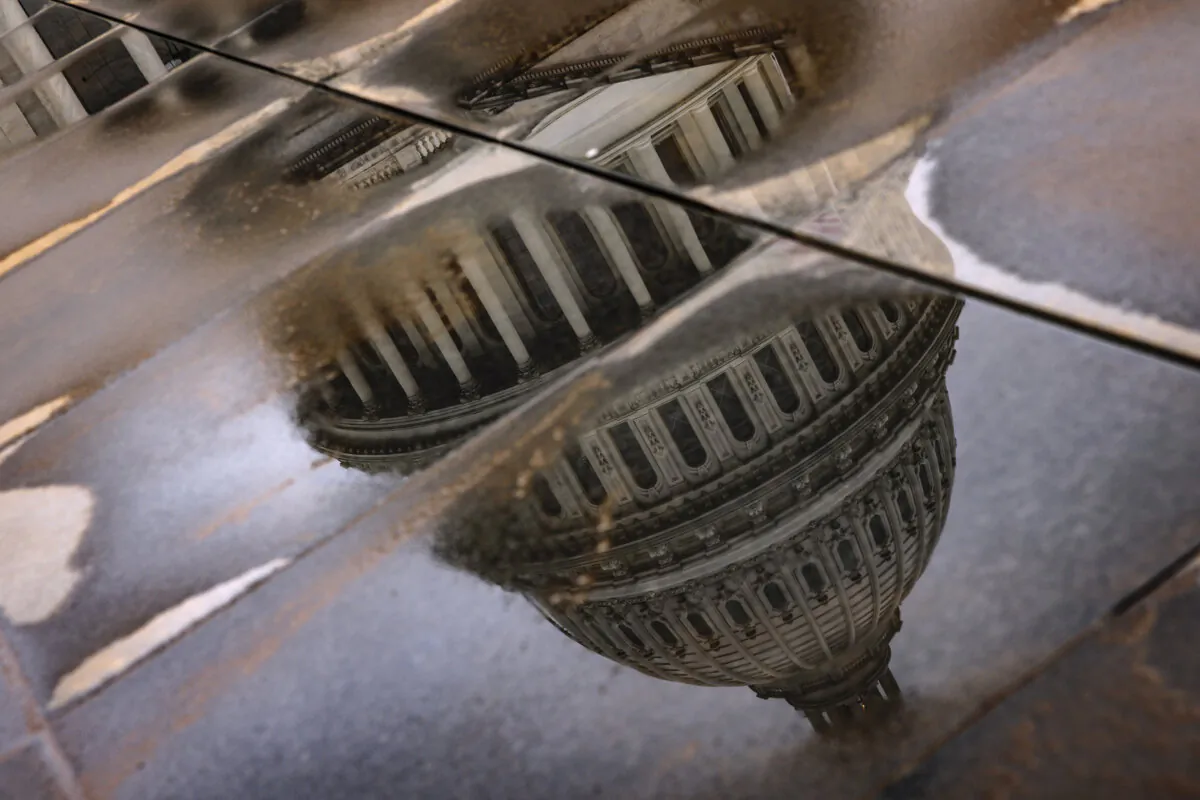 The U.S. Capitol building is seen reflected in rain puddles in Washington, D.C., on Feb. 11, 2024. (Samuel Corum/Getty Images)