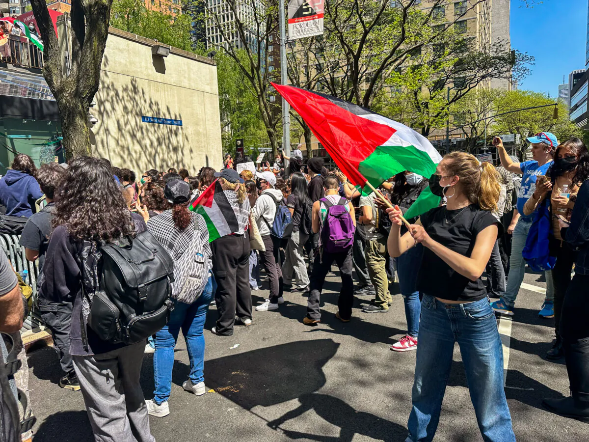 Riley Kerr waves the Palestinian flag at Fordham University on May 1, 2024. (Juliette Fairley/The Epoch Times)
