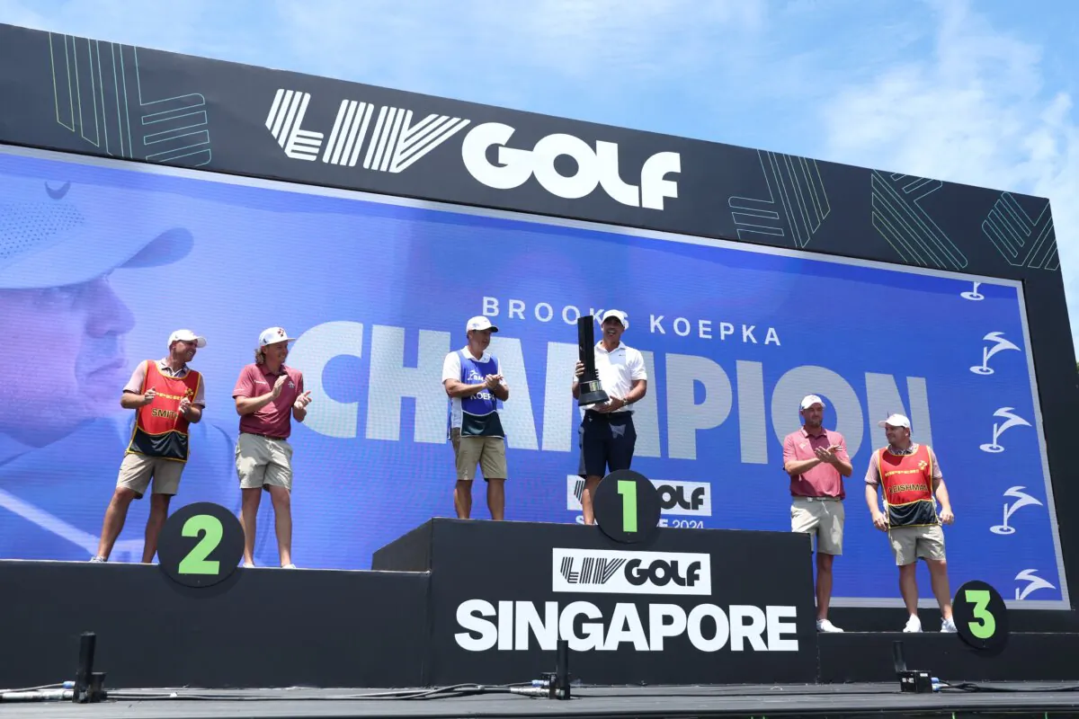 Brooks Koepka of Smash GC celebrates his win on the podium alongside second place Cameron Smith of Ripper GC and third place Marc Leishman of Ripper GC during day three of the LIV Golf Invitational–Singapore in Singapore on May 5, 2024. (Lionel Ng/Getty Images)
