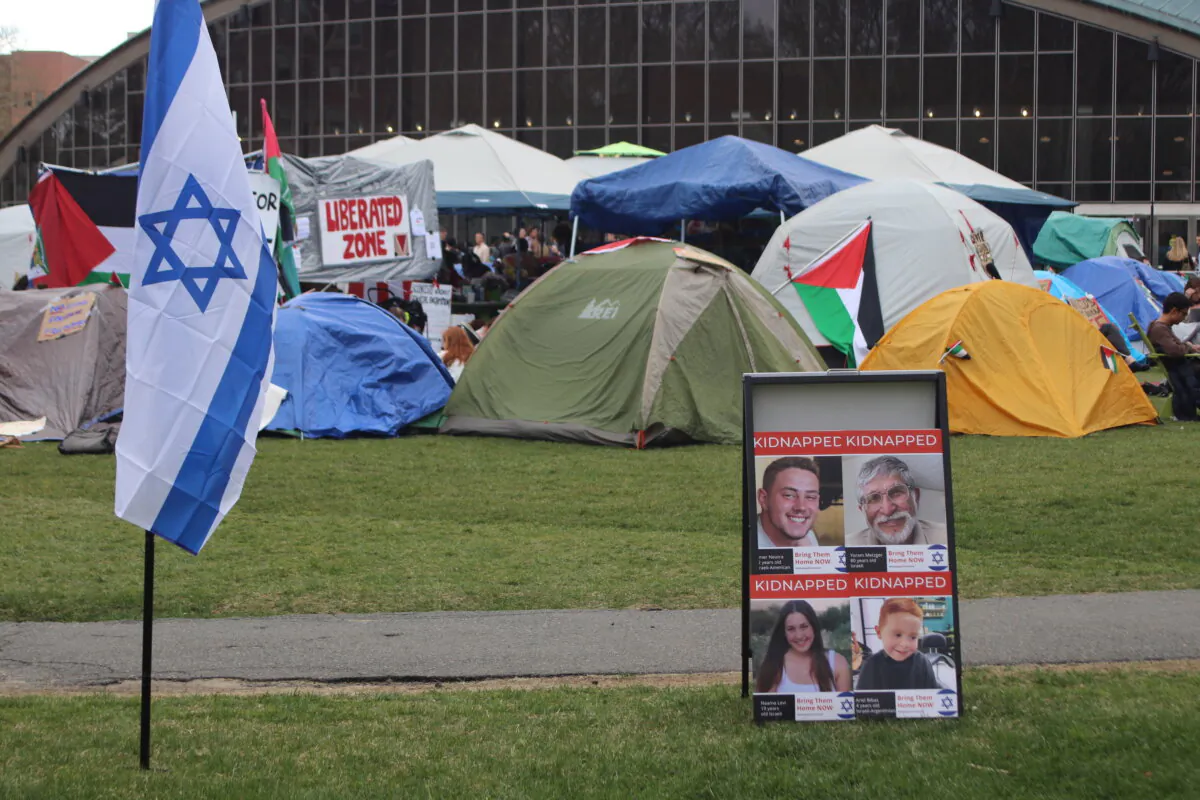 An Israeli flag positioned next to posters of Israeli hostages taken in the Oct. 7 Hamas attacks stands near a pro-Palestinian encampment at MIT in Boston, Mass., on April 29, 2024. (Courtesy of Alice Giordano)
