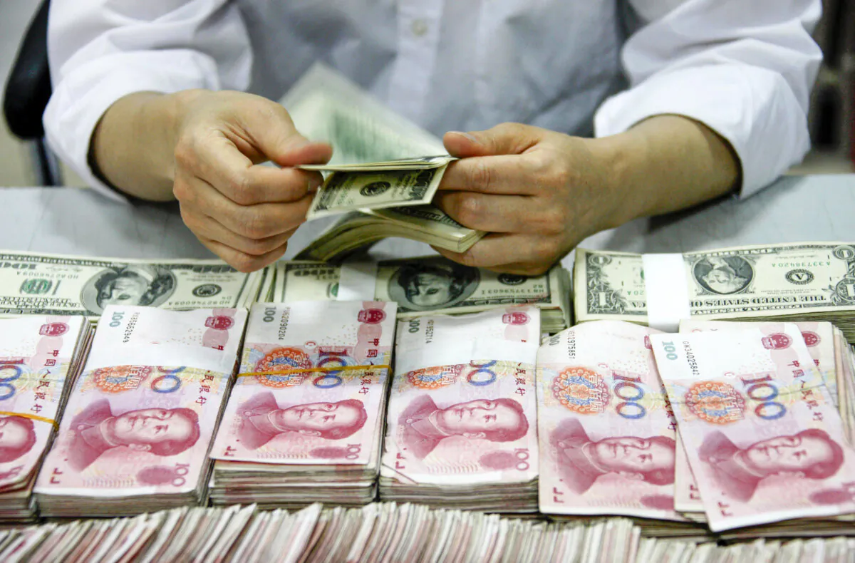 U.S. dollar notes being counted next to stacks of Chinese 100 yuan (RMB) bank notes at a bank in Huaibei, in eastern China's Anhui Province, on Sept. 24, 2013. (STR/AFP via Getty Images)