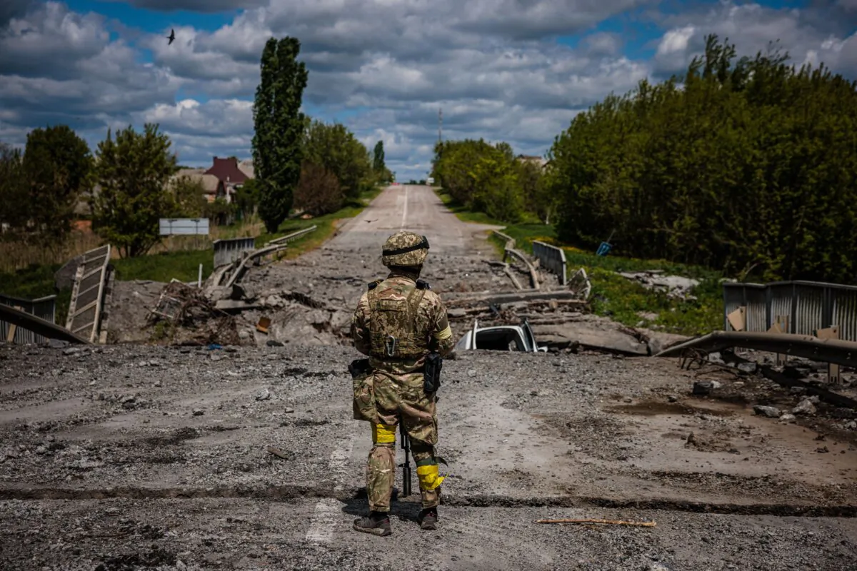 A soldier of the Kraken Ukrainian special forces unit observes the area at a destroyed bridge on the road near the village of Rus'ka Lozova, north of Kharkiv, on May 16, 2022. (Dimitar Dilkoff/ AFP via Getty Images)
