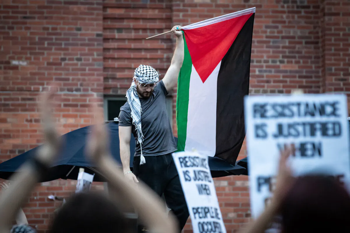 A demonstrator holds a Palestinian flag as hundreds of people rally at George Washington University, in Washington on May 7, 2024. (Allison Bailey/Middle East Images/AFP/Getty Images)
