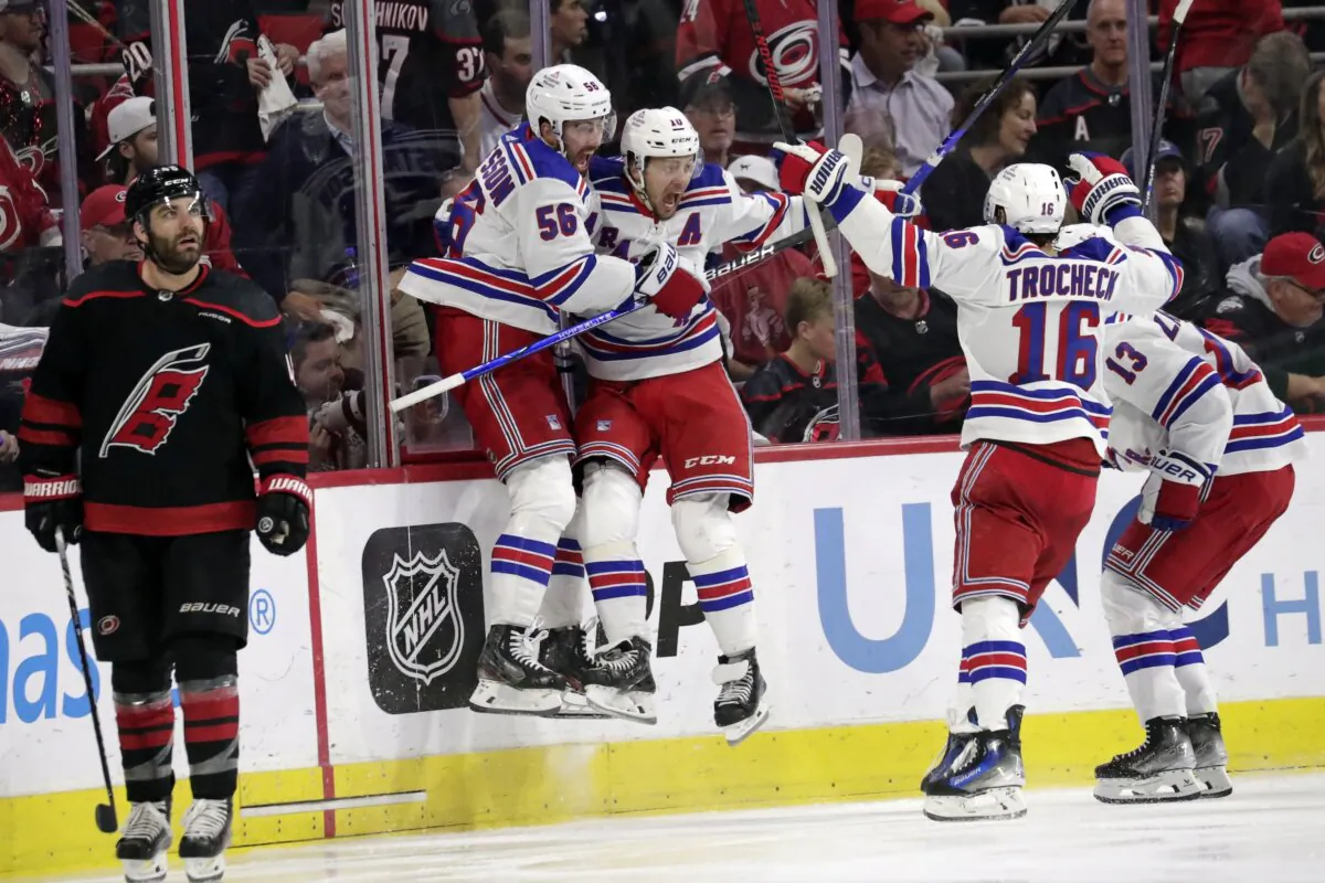 New York Rangers defenseman Erik Gustafsson (56), left wing Artemi Panarin, center Vincent Trocheck (16) and left wing Alexis Lafrenière (13) celebrate after scoring the winning goal in the overtime period in Game 3 of an NHL hockey Stanley Cup second-round playoff series in Raleigh, N.C., on May 9, 2024. (Chris Seward/AP Photo)