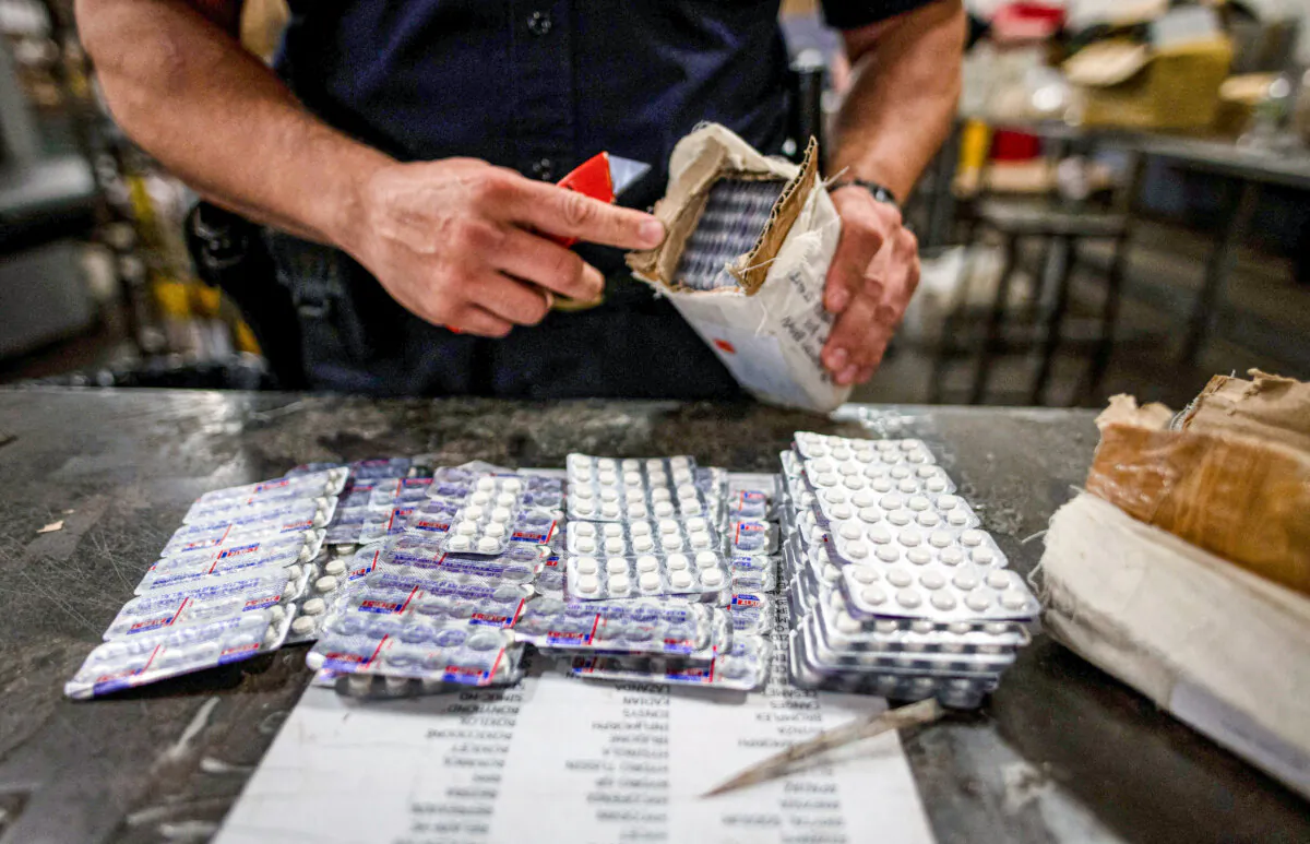 An officer from the U.S. Customs and Border Protection, Trade and Cargo Division finds Oxycodone pills in a parcel at John F. Kennedy Airport's U.S. Postal Service facility in New York on June 24, 2019. (Johannes Eisele/AFP via Getty Images)