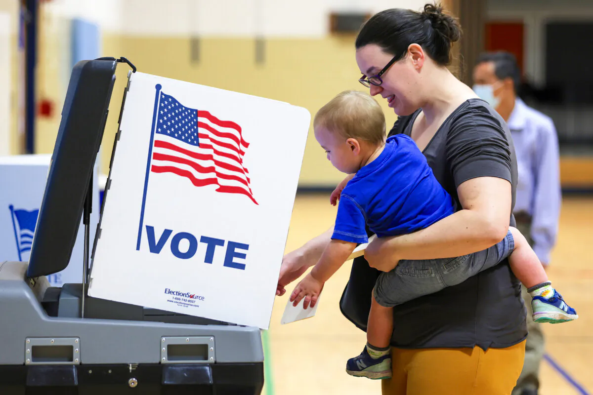 A voter casts her ballot with her child during the midterm primary election at a polling station at Rose Hill Elementary School in Alexandria, Va., on June 21, 2022. (Alex Wong/Getty Images)