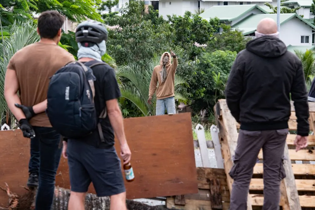 Masked residents watch an activist at the entrance to Tuband, in the Motor Pool district of Noumea on May 15, 2024, amid protests linked to a debate on a constitutional bill aimed at enlarging the electorate for upcoming elections of the overseas French territory of New Caledonia.(Delphine Mayeur /AFP via Getty Images)
