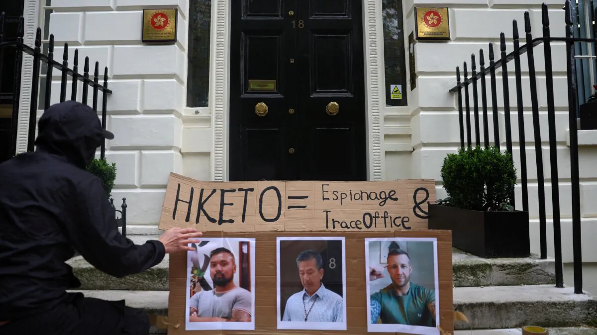 A protester places photos of three men charged with assisting Hong Kong's foreign intelligence service in Britain on the door of the Hong Kong Economic and Trade Office, in London, UK on May 14, 2024. (Toby Melville/Reuters)