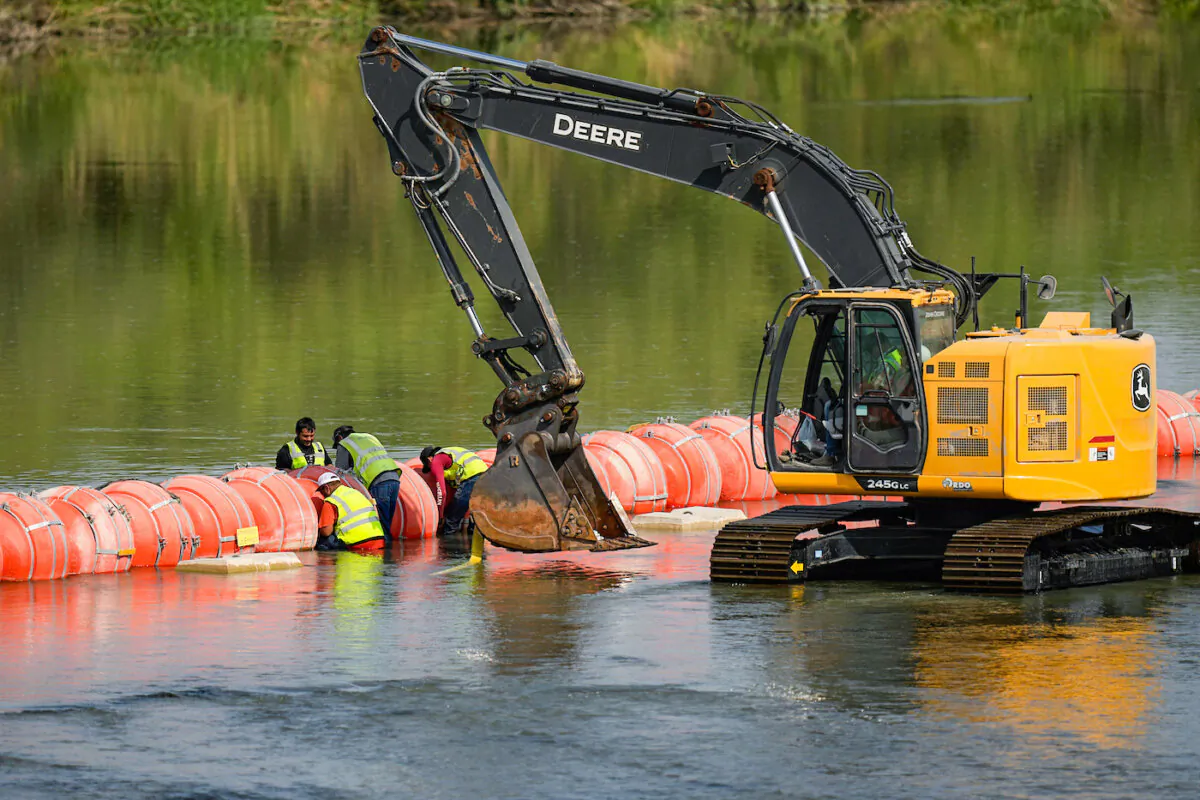 Workers make adjustments to buoys being used as a barrier along the Rio Grande, in Eagle Pass, Texas, on Aug. 21, 2023. (Eric Gay/AP Photo)