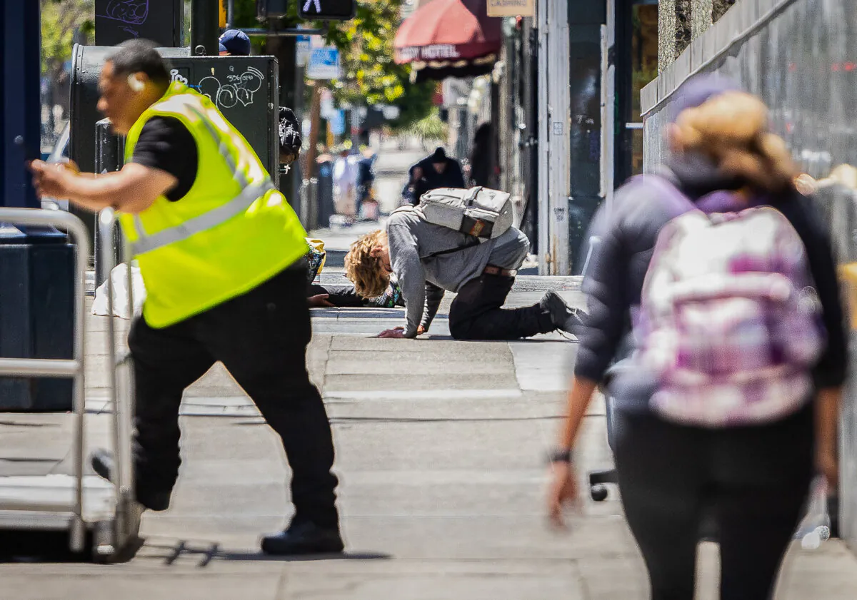 People walk around a person under the influence of drugs in the Tenderloin District of San Francisco, Calif., on May 16, 2024. (John Fredricks/The Epoch Times)
