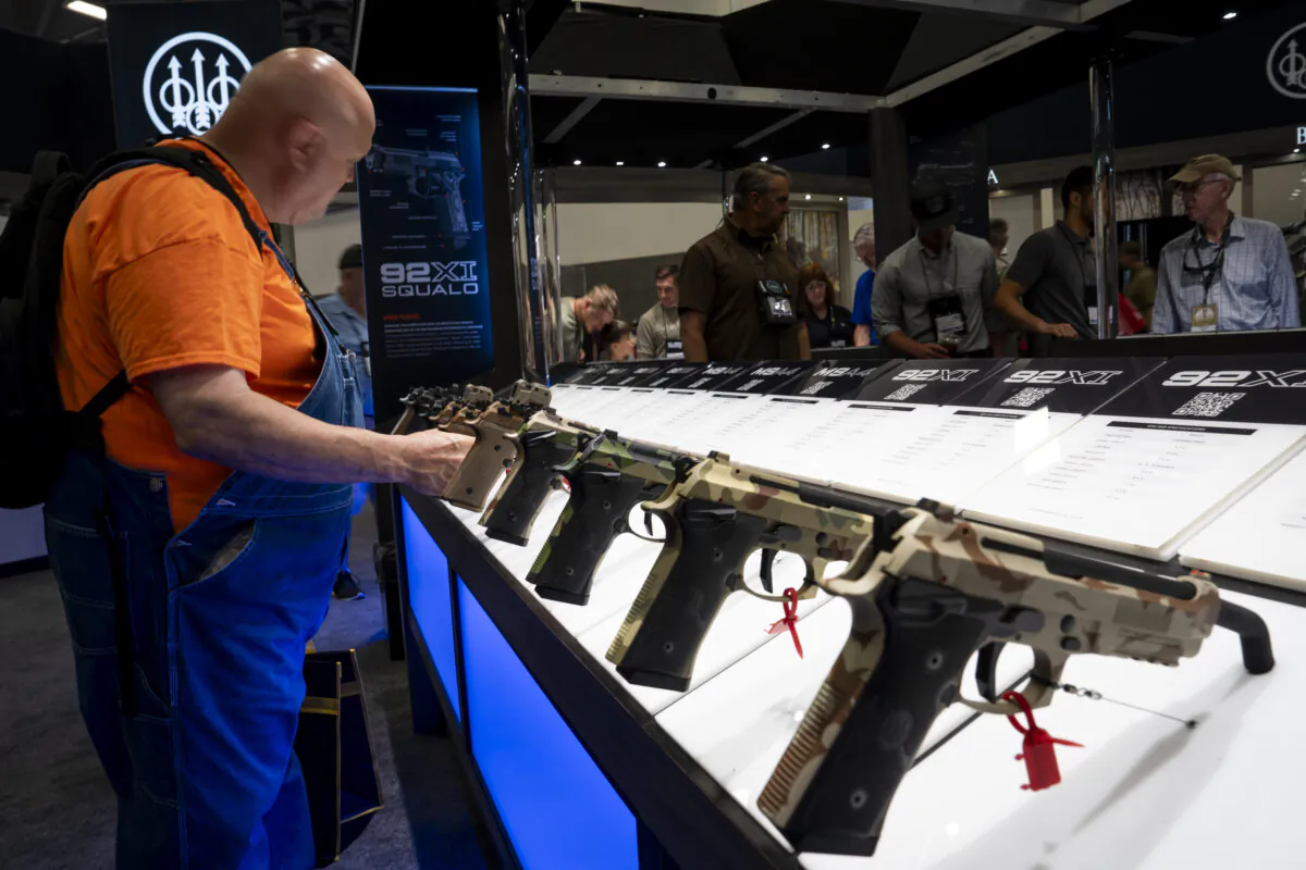 People examine firearms at the National Rifle Association exhibits at the Kay Bailey Hutchison Convention Center in Dallas on May 18, 2024. (Madalina Vasiliu/The Epoch Times)