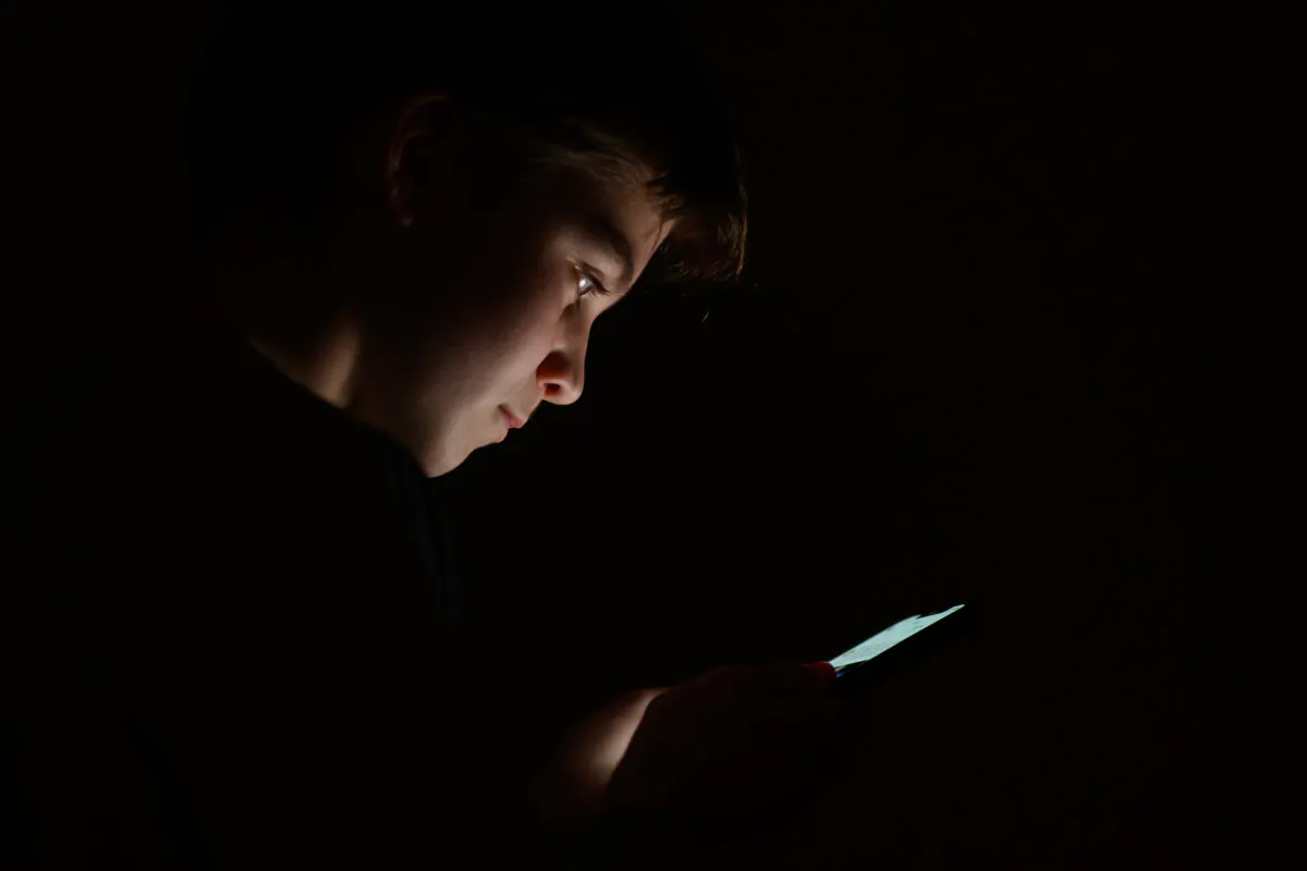 A teenage child looks at the screen of a mobile phone in London, England, on Jan. 17, 2023. (Leon Neal/Getty Images)