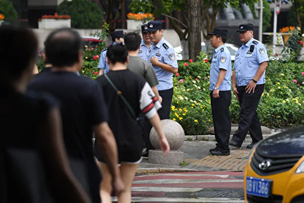 Police wait to check the identification of passersby as they search for petitioners near China's Banking Regulatory Commission in Beijing on August 6, 2018 - Hundreds of police swarmed the streets of Beijing's financial district on August 6 as Chinese authorities aggressively quashed a planned protest against losses sustained by peer-to-peer (P2P) lending platforms. (Photo by GREG BAKER / AFP)