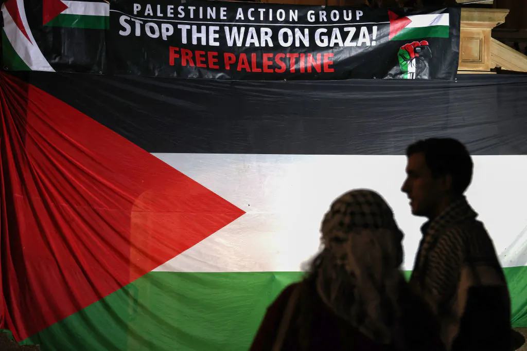 Pro-Palestinian protesters stand in front of a large flag and banner at a rally in Sydney on May 15, 2024. (DAVID GRAY/AFP via Getty Images)