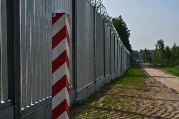 KUZNICA, POLAND - JUNE 30: A Polish border marker stands by the Metal border wall on June 30, 2022 in Kuznica, Poland. At a cost of 353 million euros, the newly erected 5.5 metre metal wall is 186 km long and covers almost half of the total border length of 418 km between Poland and Belarus, designed with sensors and cameras to keep out certain migrants. The project has raised concerns from human rights and environmental activists fearing that migrants fleeing conflict will not be able to apply for asylum, as well as the harmful effects for the fauna and flora of the forest zone at the border. (Photo by Omar Marques/Getty Images)