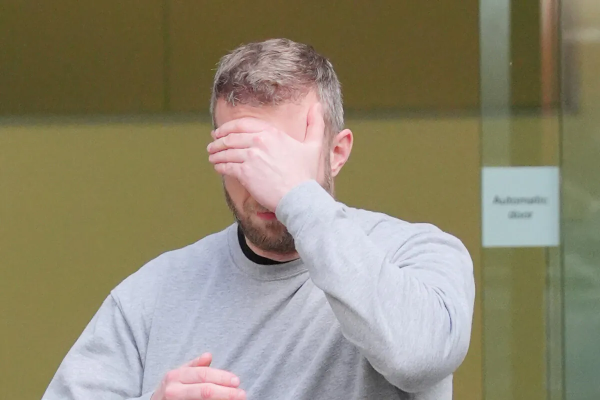 Matthew Trickett covering his face as he leaves Westminster Magistrates' Court after appearing in court accused of assisting the Hong Kong intelligence service, in London on May 21, 2024. (Jonathan Brady/PA)