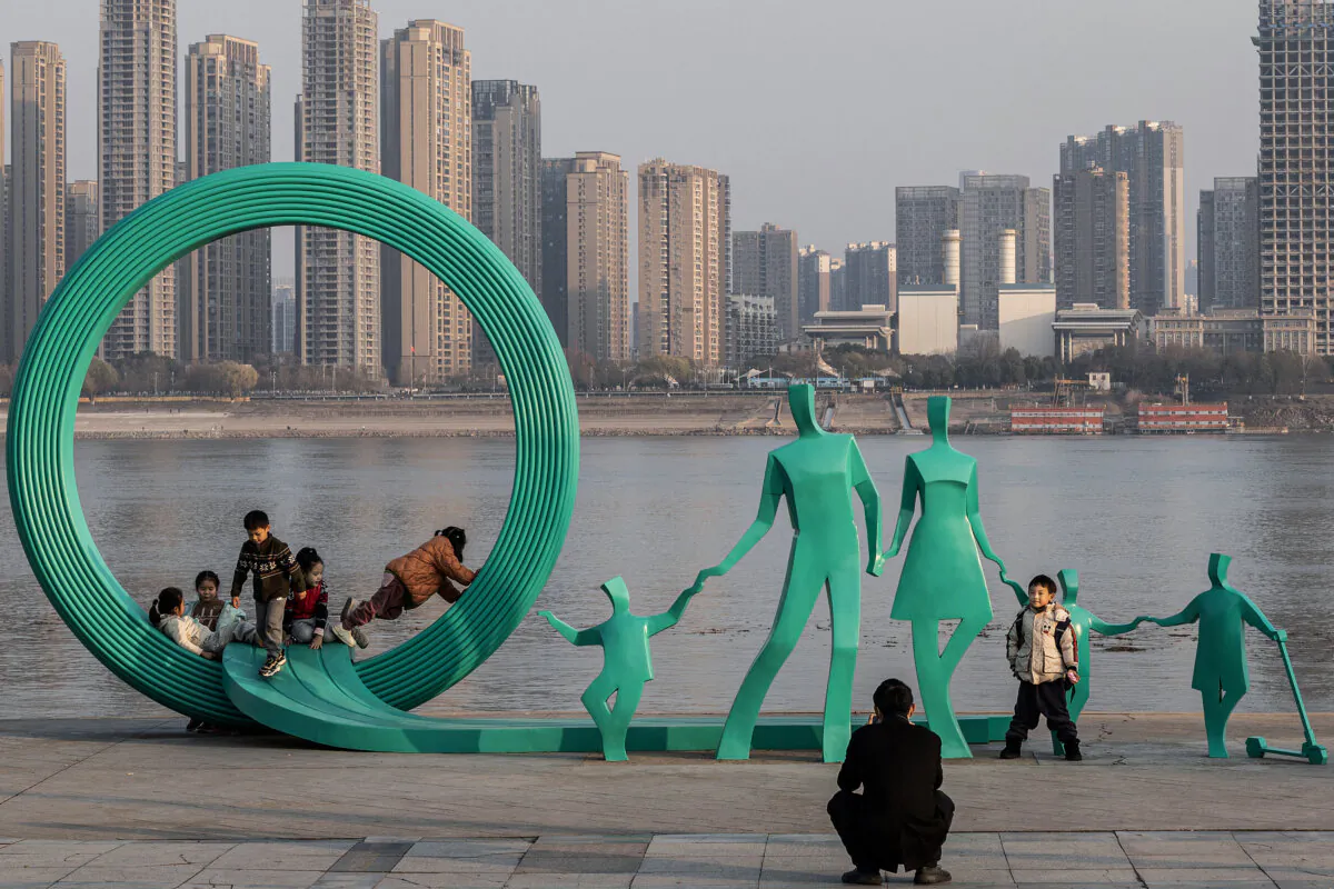 People posing next to a newly renovated statue of a pair of parents and three children in Hankou Park next to Yangtze River in Wuhan, in China's central Hubei province on Jan. 5, 2024. (STR/AFP via Getty Images)
