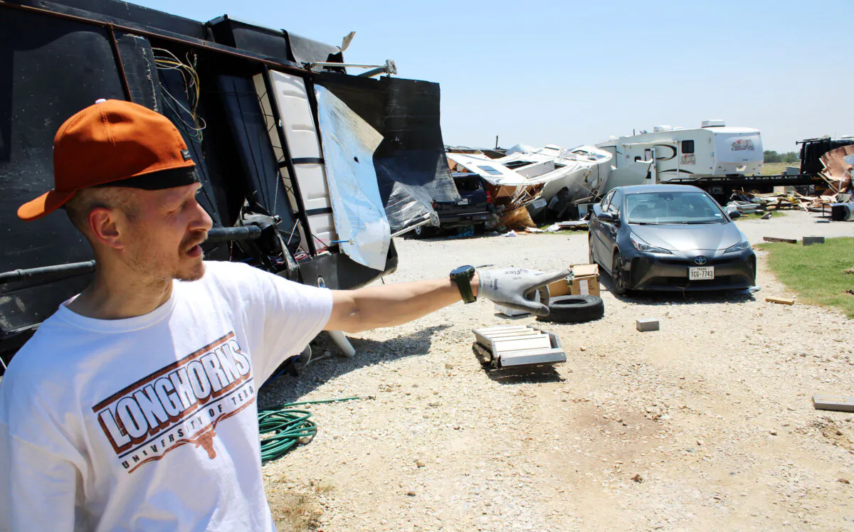 Brandon Finney stands in front of his overturned camper on May 26, 2024 as he recounts the tornado that hit the RV park in which he lives the night before. (Michael Clements/The Epoch Times)