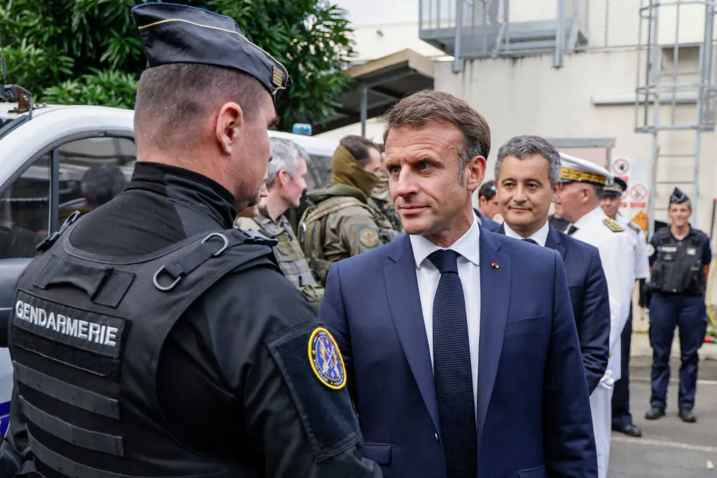 French President Emmanuel Macron visits the central police station with France's Minister for Interior and Overseas Gerald Darmanin (R) in Noumea, France's Pacific territory of New Caledonia on May 23, 2024. France's president made a long-haul trip to the restive Pacific territory of New Caledonia on on May 23, urging a "return to peace" after deadly rioting, and vowing thousands of military reinforcements will be deployed for "as long as necessary". (Photo by Ludovic MARIN / POOL / AFP) (Photo by LUDOVIC MARIN/POOL/AFP via Getty Images)