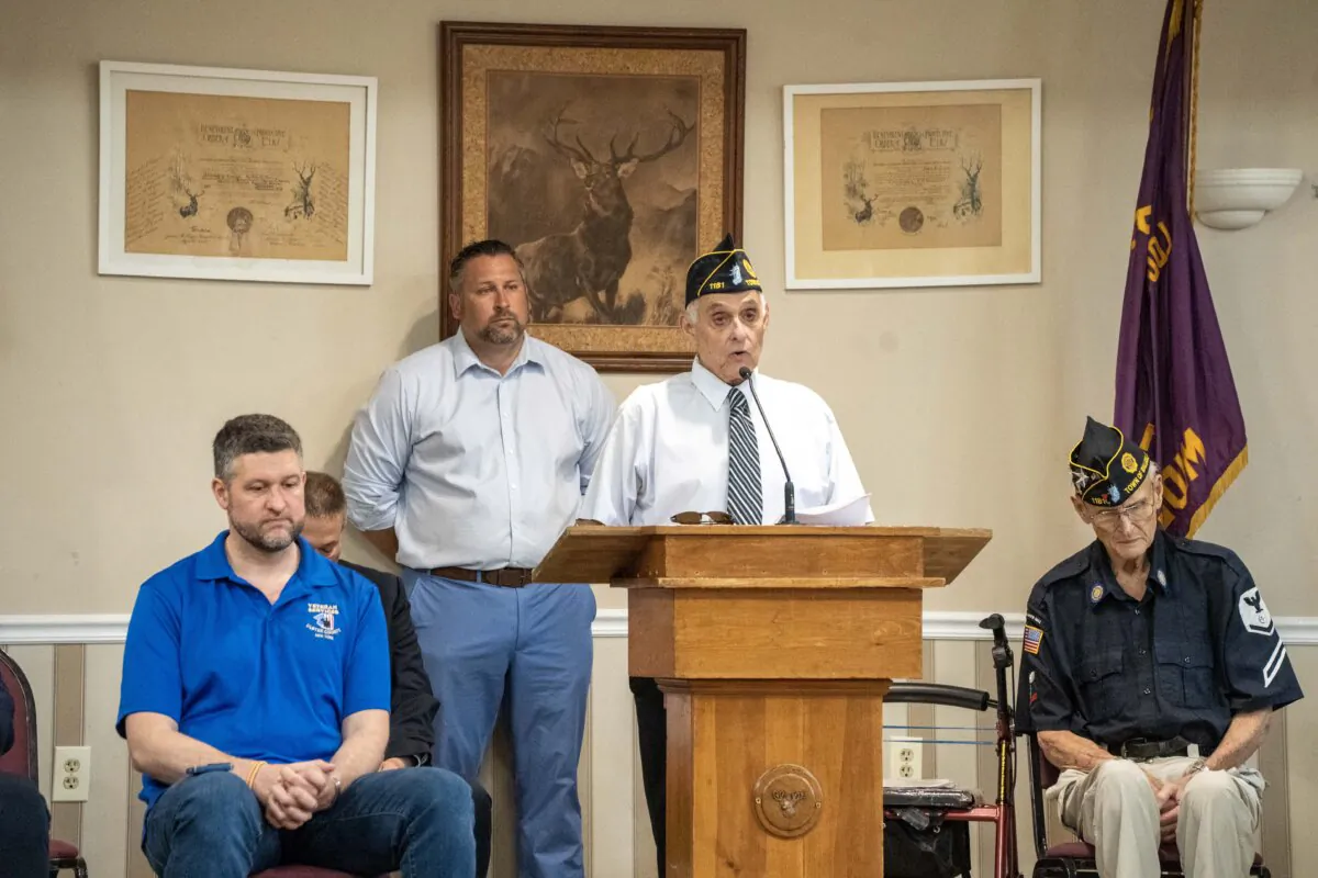 Barry Schnipper (C), flanked by Congressman Pat Ryan (L) and veteran Tom Nosworthy (R) reads a letter by a soldier that died in action at a Memorial Day service held in Middletown, N.Y., on March 27, 2024. (Cara Ding/The Epoch Times)