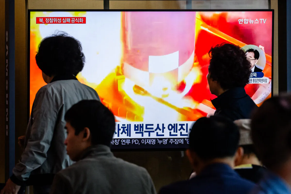 People walk past a television showing file footage during a news report at a train station in Seoul on May 28, 2024, after North Korea said late Monday that the rocket carrying its "Malligyong-1-1" reconnaissance satellite exploded minutes after launch due to a suspected engine problem. (ANTHONY WALLACE/AFP via Getty Images)