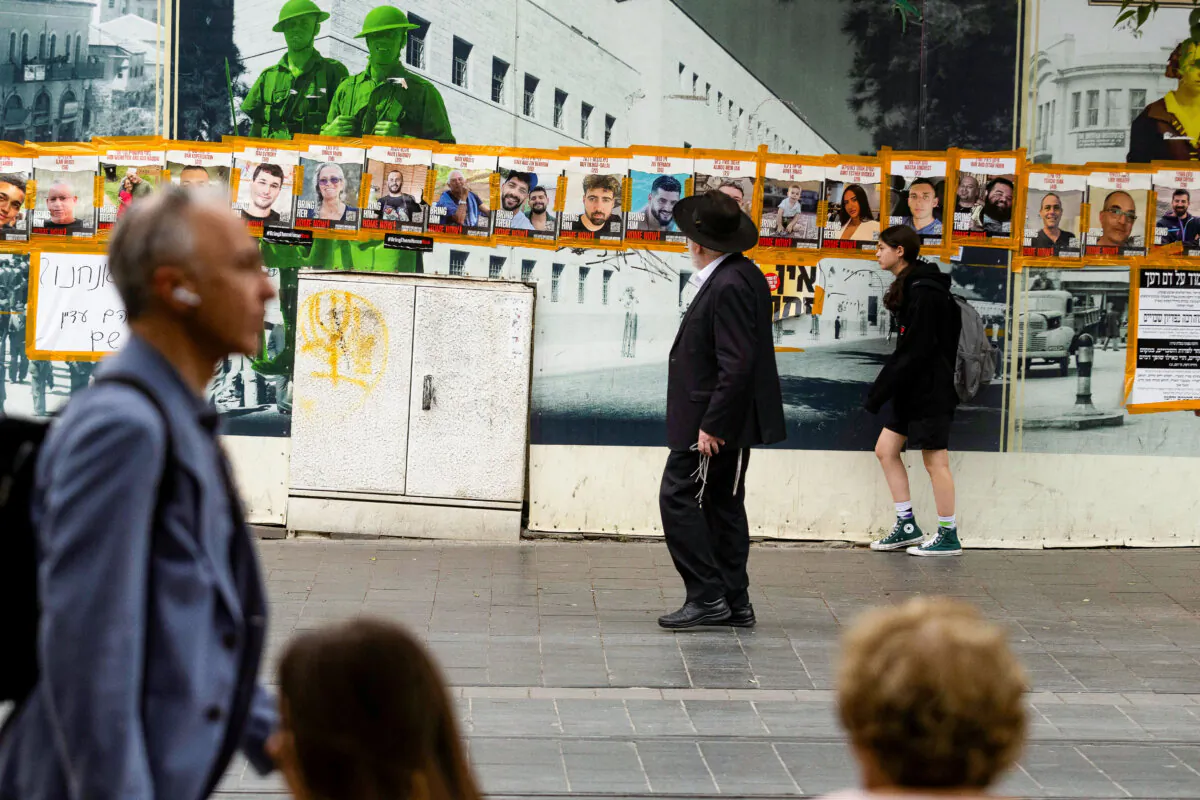 People walk by photos of hostages held in the Gaza Strip by Hamas that hang on a wall in Jaffa Street in Jerusalem on May 20, 2024. (Amir Levy/Getty Images)