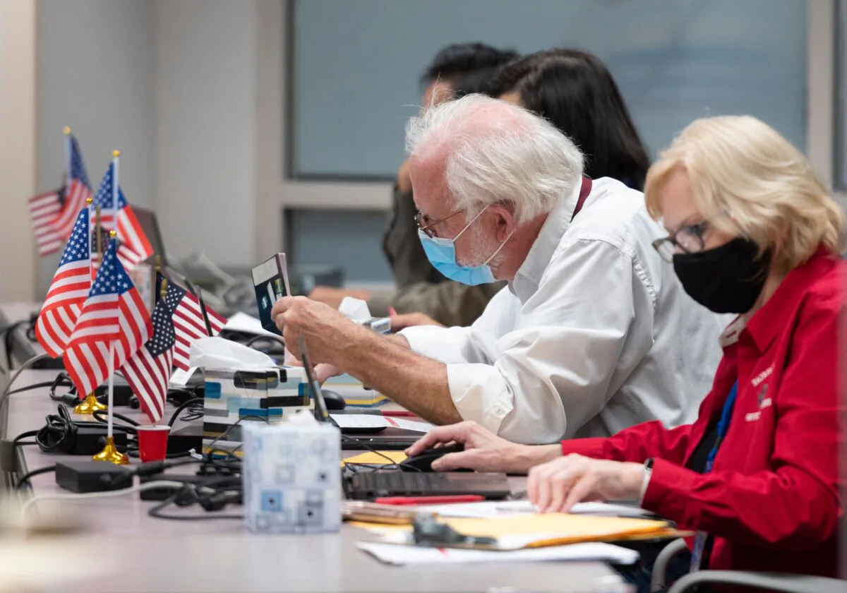 A man checks the ID of a voter before giving them a ballot at an early voting location in Fairfax, Va., on Sept. 18, 2020. (ANDREW CABALLERO-REYNOLDS/AFP via Getty Images)