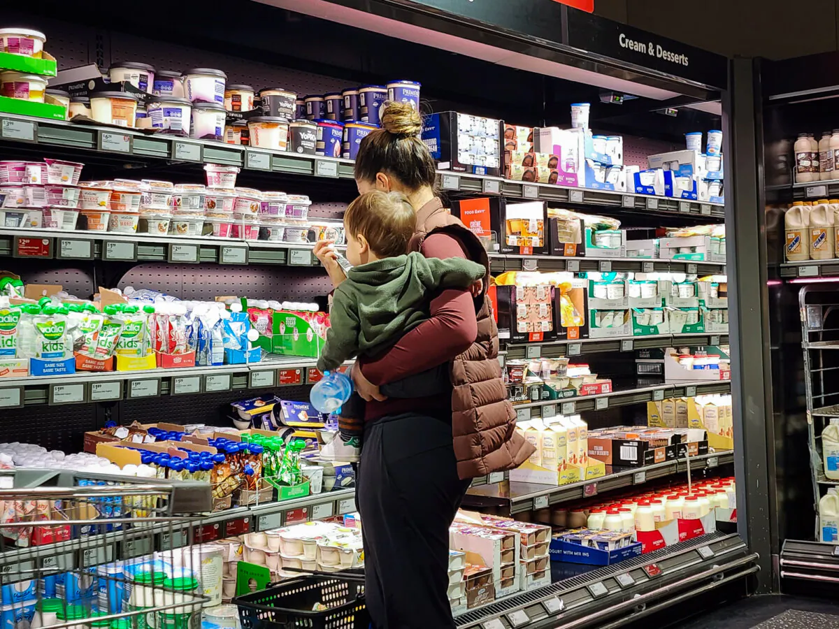 A woman shops while holding her child in a supermarket in Albany, Western Australia, on April 11, 2024. (Susan Mortimer/The Epoch Times)
