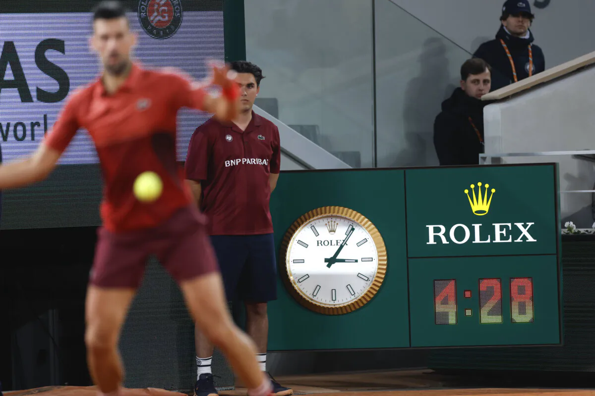 Serbia's Novak Djokovic plays a shot against Italy's Lorenzo Musetti as the clock indicates the match time played in the fifth set of their third round match of the French Open tennis tournament at the Roland Garros stadium in Paris on June 2, 2024. (Jean-Francois Badias/AP Photo)
