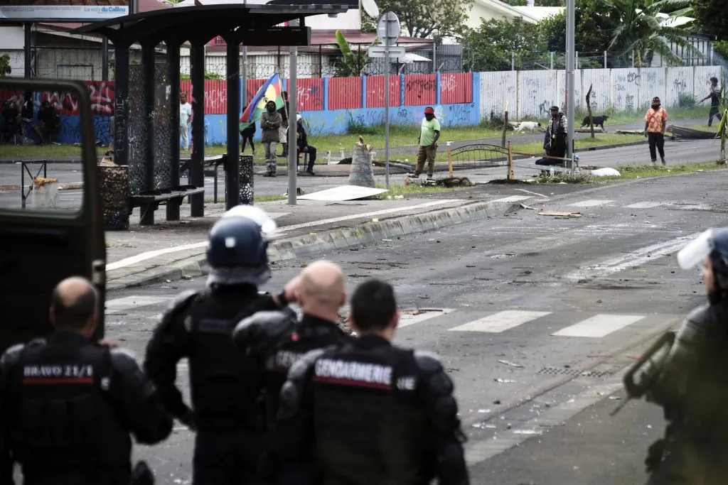 French gendarmes stand guard near independantists at the entrance of the Riviere Salee disctrict, in Noumea, France's Pacific territory of New Caledonia, on May 29, 2024. Riots sparked by a constitutional reform project broke out on May 13. France has lifted a state of emergency across the territory after two weeks of unrest in which seven people died and hundreds were injured (Photo by Theo Rouby / AFP) (Photo by THEO ROUBY/AFP via Getty Images)