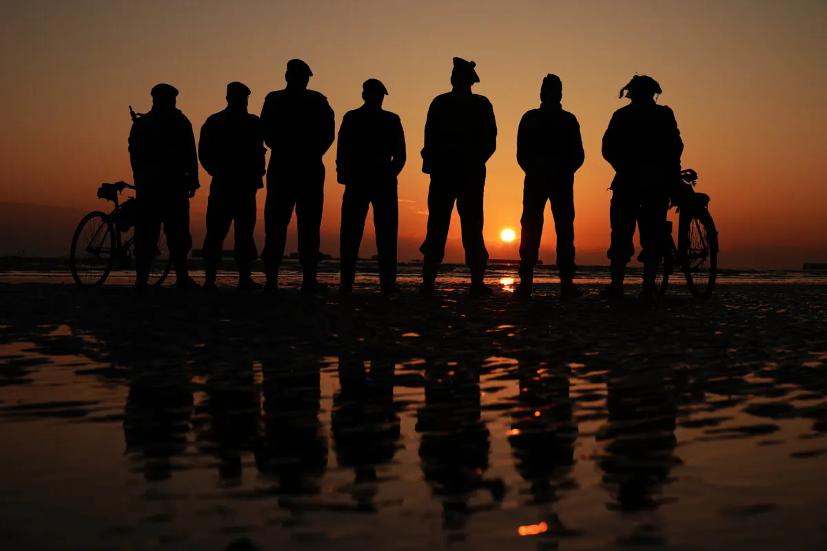 People commemorating the 80th anniversary of the D-Day landings, on Gold Beach in Arromanches Normandy, France, on June 6, 2024. (Aaron Chown/PA Wire)