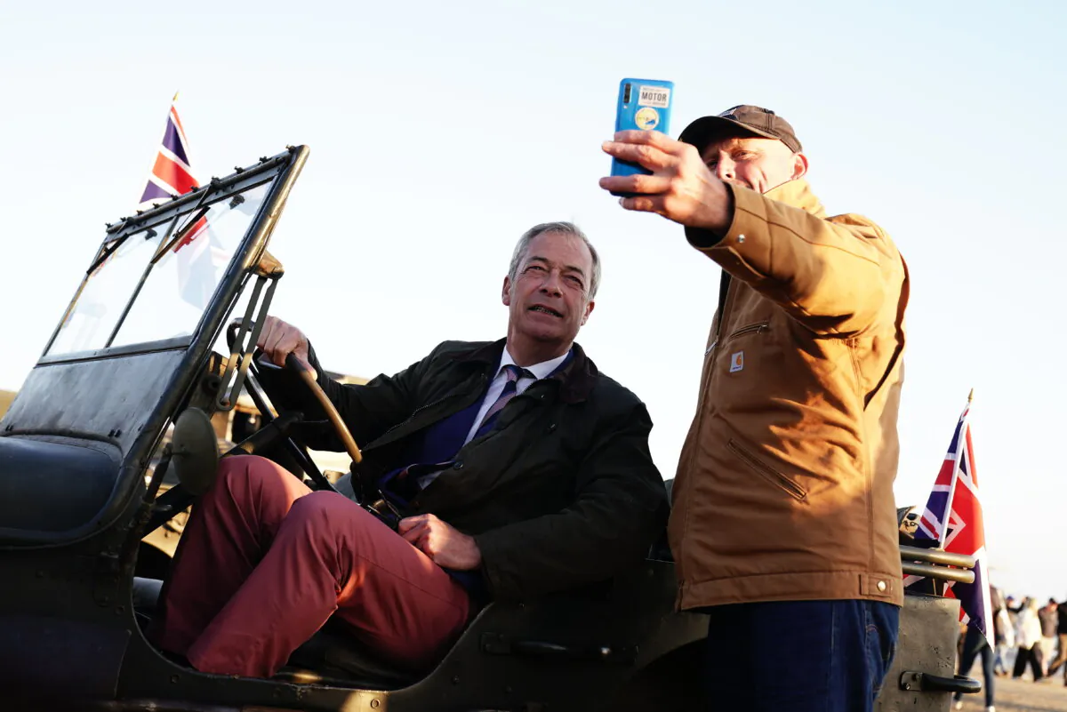 A man takes a selfie with the leader of Reform UK Nigel Farage (L) on Gold Beach in Arromanches, Normandy, France, on June 6, 2024. (Aaron Chown/PA)