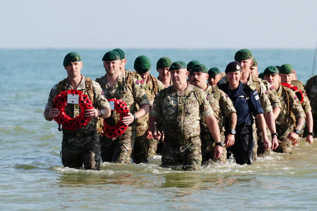 Royal Marines of 47 Commando and civilians commemorate the 80th anniversary of the D-Day landings by landing at a beach at Asnelles in Normandy, France, on June 6, 2024. (Aaron Chown/PA Wire)