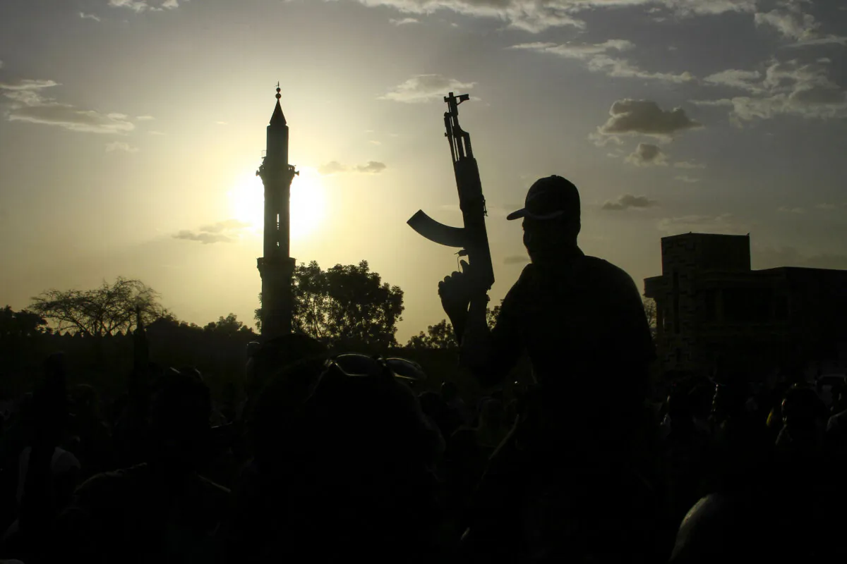 A fighter loyal to Sudan's army chief, Abdel Fattah al-Burhan, holds up a weapon backdropped by the minaret of a mosque, during a graduation ceremony in the southeastern Gedaref state of Sudan on May 27, 2024. (AFP via Getty Images)