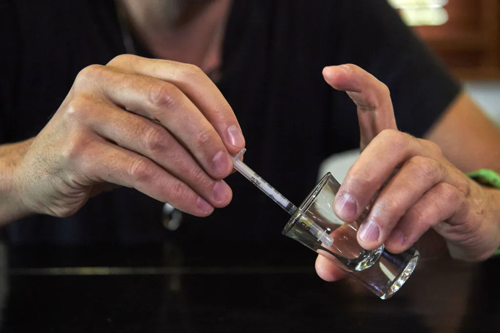A man gathers snake venom with a syringe after extracting the venom from a Pope's Pit Viper in London on Nov.  9, 2017.
(NIKLAS HALLE'N/AFP via Getty Images)