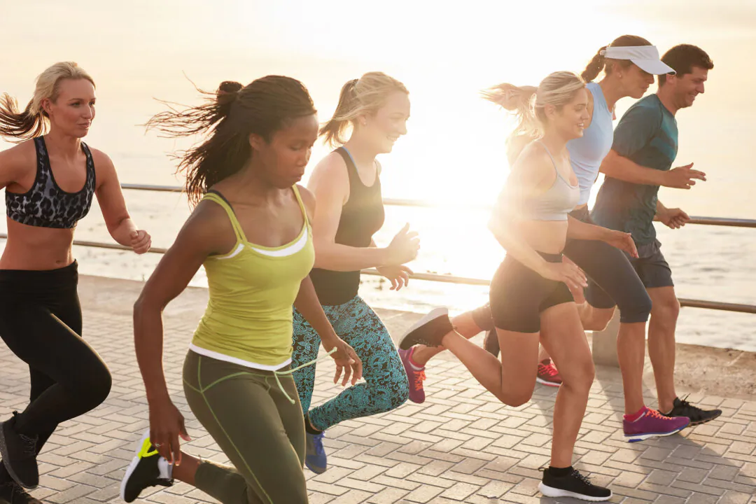 Group of young people sprinting outdoors at sunset. 