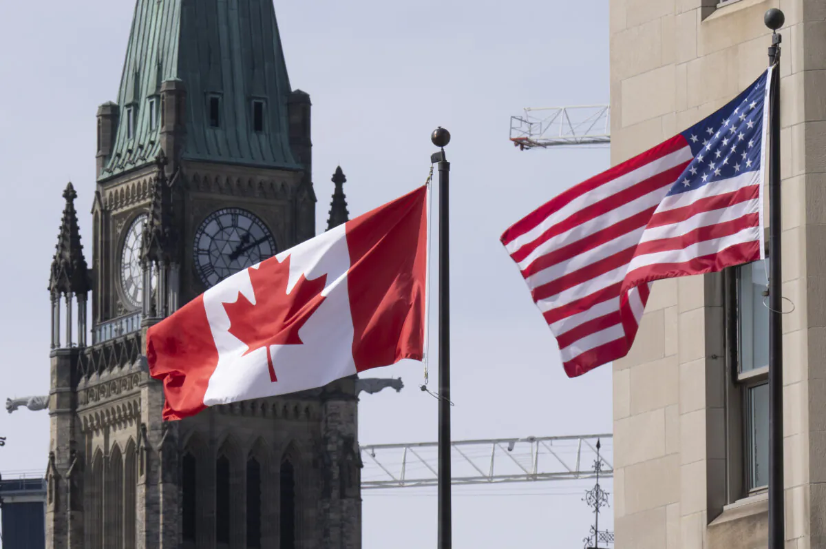 Canadian and U.S. flags are seen flying near Parliament Hill in Ottawa on March 22, 2023. (The Canadian Press/Adrian Wyld)