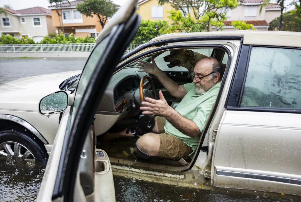 Mike Viesel, and his dog Humi, wait in his flooded car for a tow truck after their car stalled on Taft Street due to heavy rain flooding the neighborhood of Hollywood, Fla., on June 12, 2024. (Matias J. Ocner/Miami Herald via AP)
