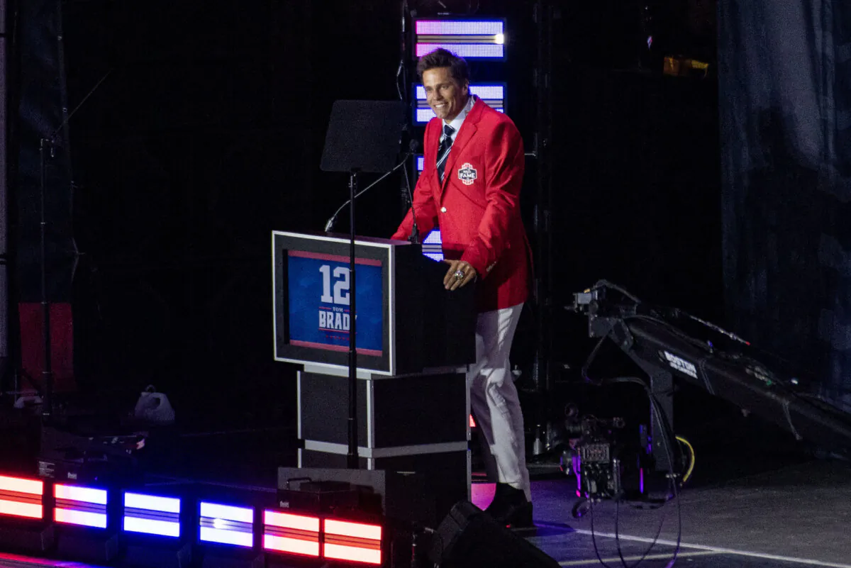 Former New England Patriots quarterback Tom Brady wears his red Patriots Hall of Fame induction jacket as he speaks during the 2024 induction ceremony at Gillette Stadium in Foxborough, Massachusetts, on June 12, 2024. (Joseph Prezioso/AFP via Getty Images)