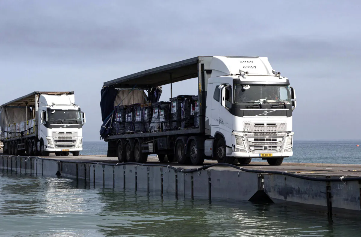 Trucks loaded with humanitarian aid from the United Arab Emirates and the United States Agency for International Development cross the Trident Pier before arriving on the beach on the Gaza Strip on May 17, 2024. (Staff Sgt. Malcolm Cohens-Ashley/U.S. Army via AP)