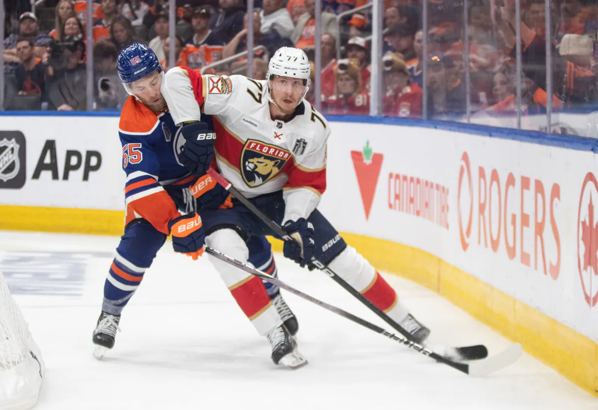 Florida Panthers' Niko Mikkola (L) and Edmonton Oilers' Dylan Holloway battle for the puck during second period Game 4 action of the NHL Stanley Cup final in Edmonton on June 15, 2024. (The Canadian Press/Jason Franson)