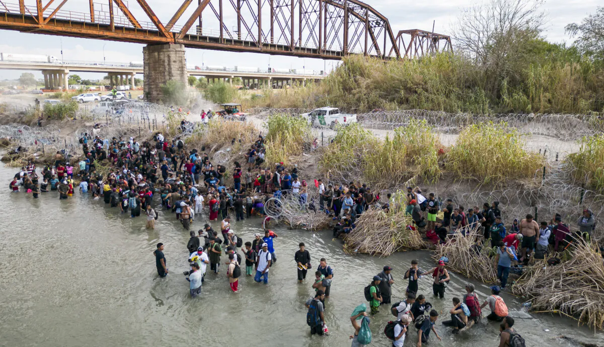 Illegal immigrants wait in the Rio Grande for an opening in the razor wire barrier to cross into the United States, in Eagle Pass, Texas, on Sept. 25, 2023. (Andrew Caballero-Reynolds/AFP via Getty Images)