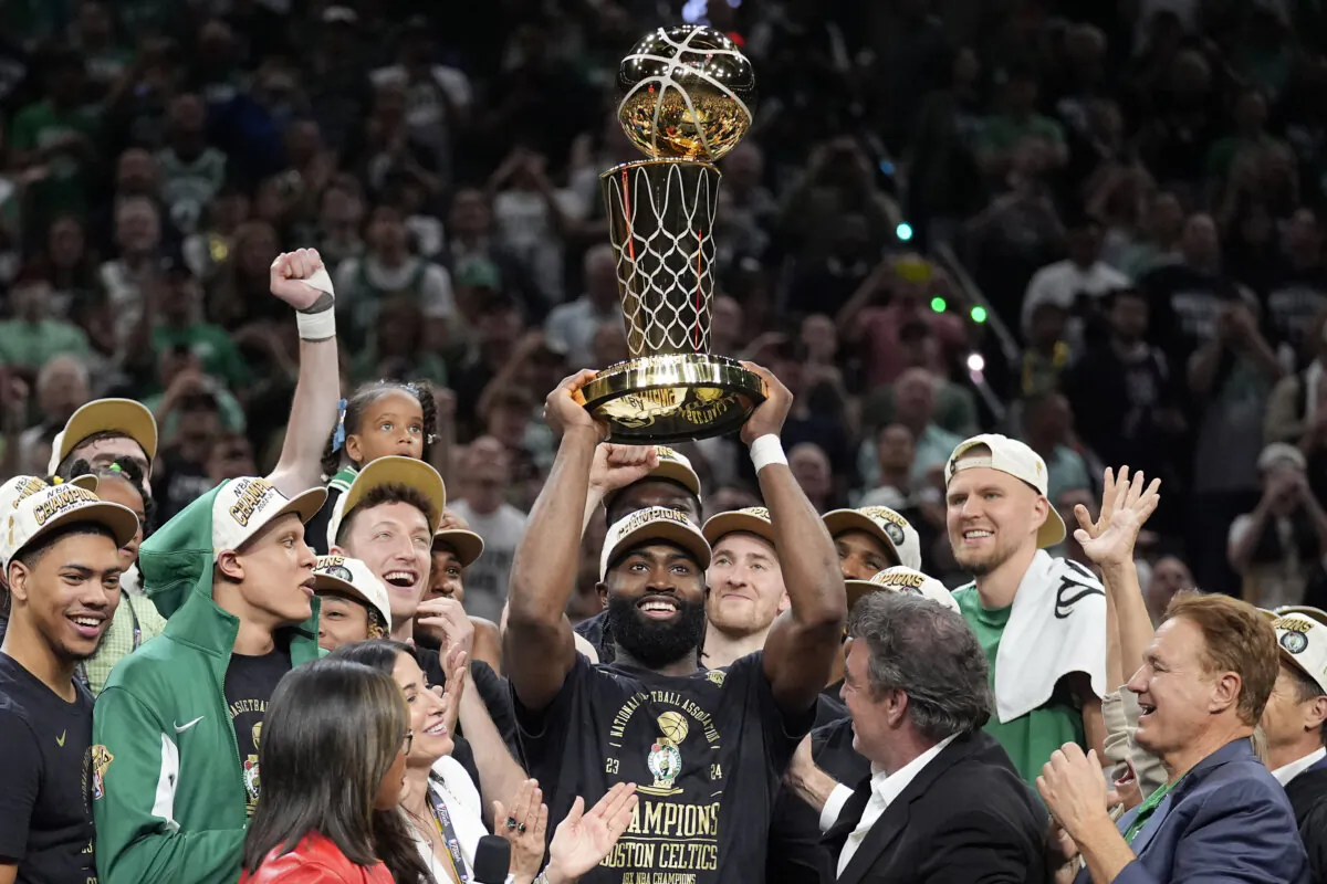 Boston Celtics guard Jaylen Brown (C) holds up the Larry O'Brien Trophy as he and the team celebrate after beating the Dallas Mavericks in Game 5 of the NBA Finals in Boston on June 17, 2024. (Charles Krupa/AP Photo)