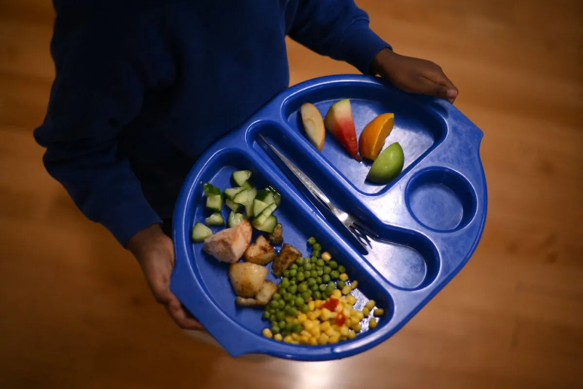 A child carries a tray with food during lunch break at St. Mary's RC Primary School, in Battersea, south London, on Nov. 29, 2022. (Daniel Leal/AFP via Getty Images)