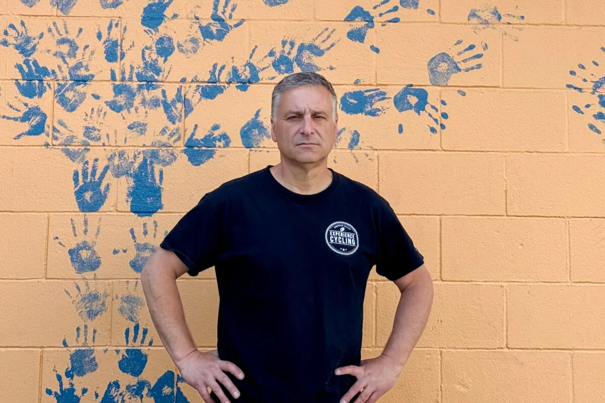 Will Arnold stands by a mural outside his shop, Experience Cycling, in Duncan, B.C., on June 12, 2024. (Courtesy of Will Arnold)