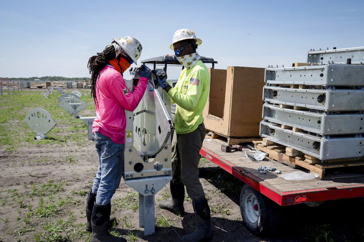 Construction workers install actuators for tilting panels at a solar energy site that is being developed in Bowling Green, Fla., on March 24, 2021. (Reuters/Dane Rhys)